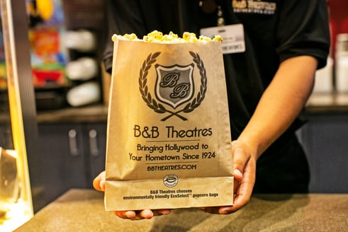staff handing popcorn to camera