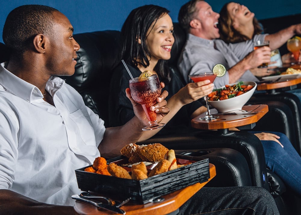 Friends enjoying a meal and drinks at their movie seat
