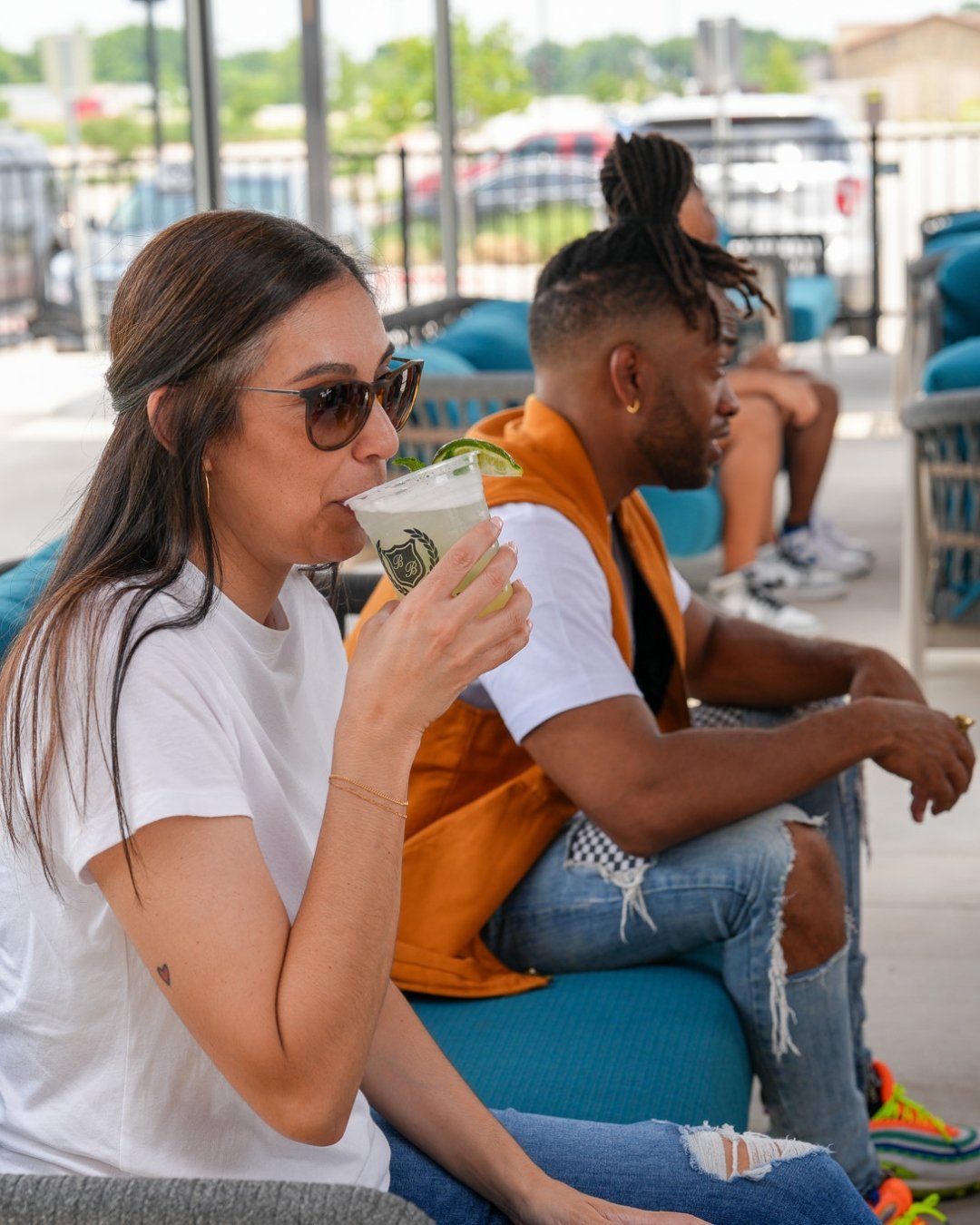 woman and man sitting in blue outdoor patio furniture. woman is sipping a drink. man is leaned forward in discussion