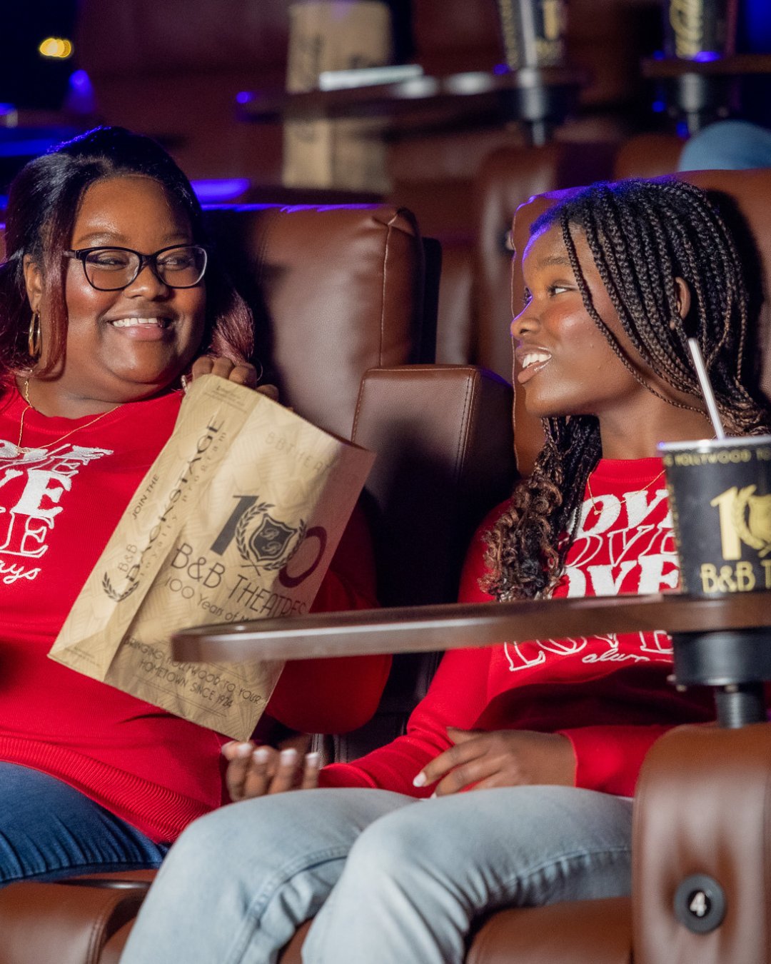 2 guests smiling at each other holding a popcorn bag