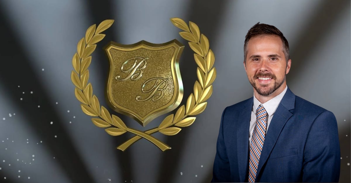 B&B gold logo next to a man smiling into the camera. 5 spotlights in the background aimed towards the top of the image.