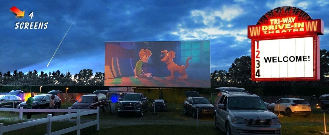 view of the tri-way drive in theater with the cars and the screen showing a scooby doo movie