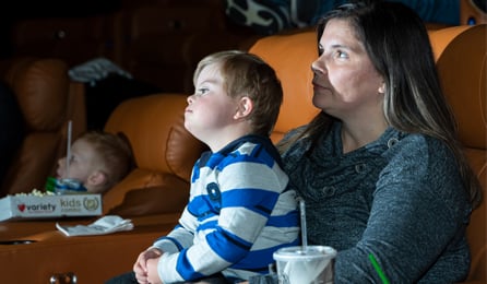 woman with son on her lap looking at movie screen