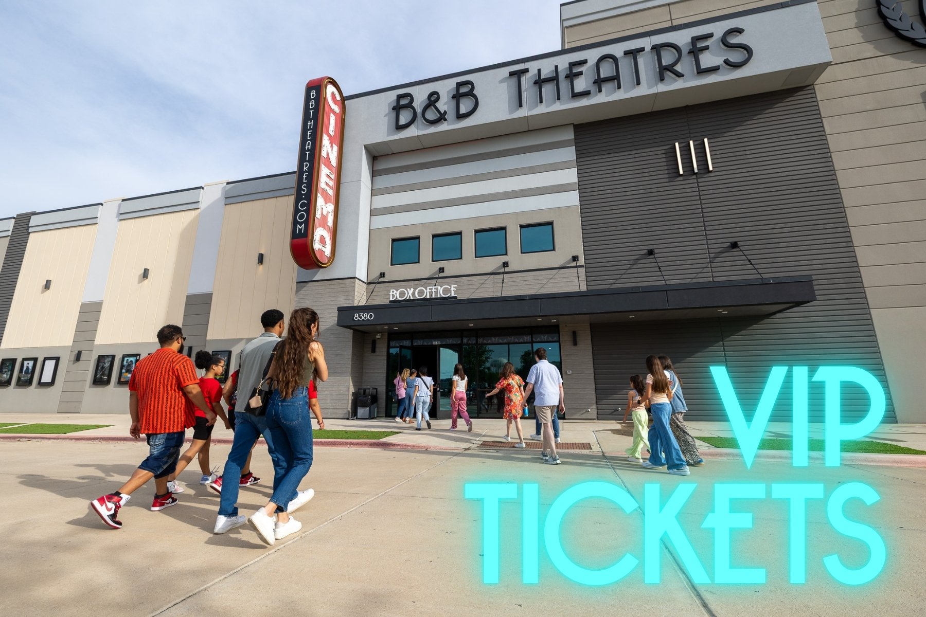 external photo of b&b theatres building. groups of people walking into front door that says "box office" 14 people in total a range of adults & kids.