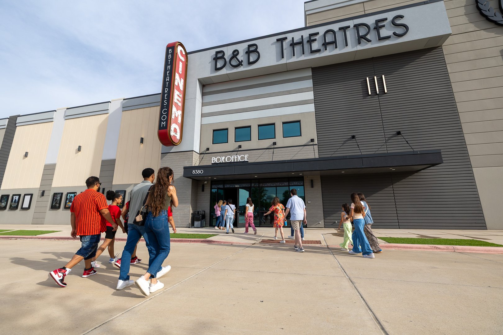 exterior of building. multiple groups of people walking towards the front door.