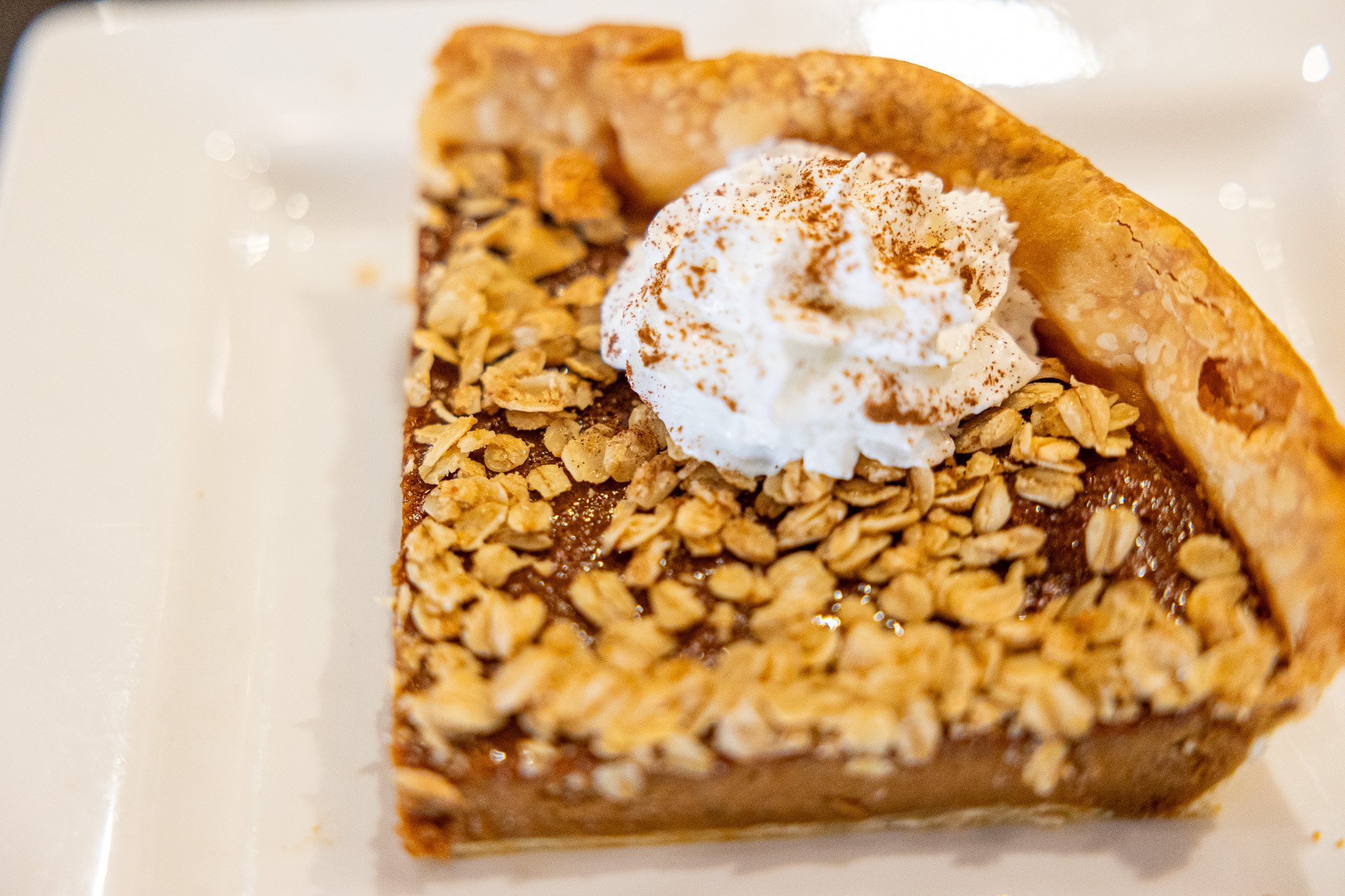 giant slice of apple butter pie topped with dollop of whipped cream and sprinkled with cinnamon
