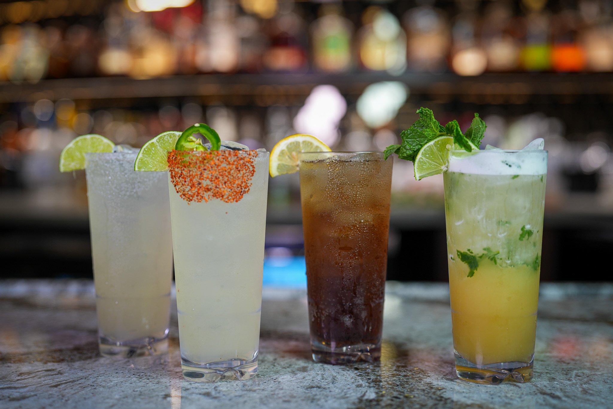 4 tall cocktails (L to R): Margarita, Spicy Margarita, Long Island Iced Tea, Pineapple Mojito