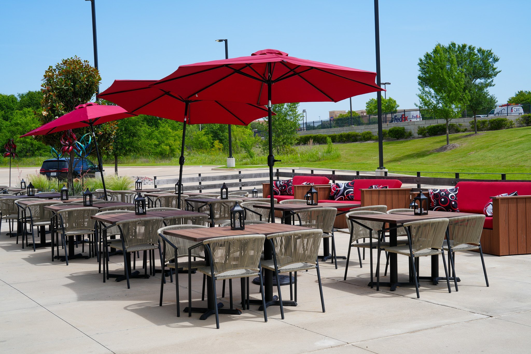 outdoor patio with chairs, tables, red umbrellas, and outdoor couches/benches