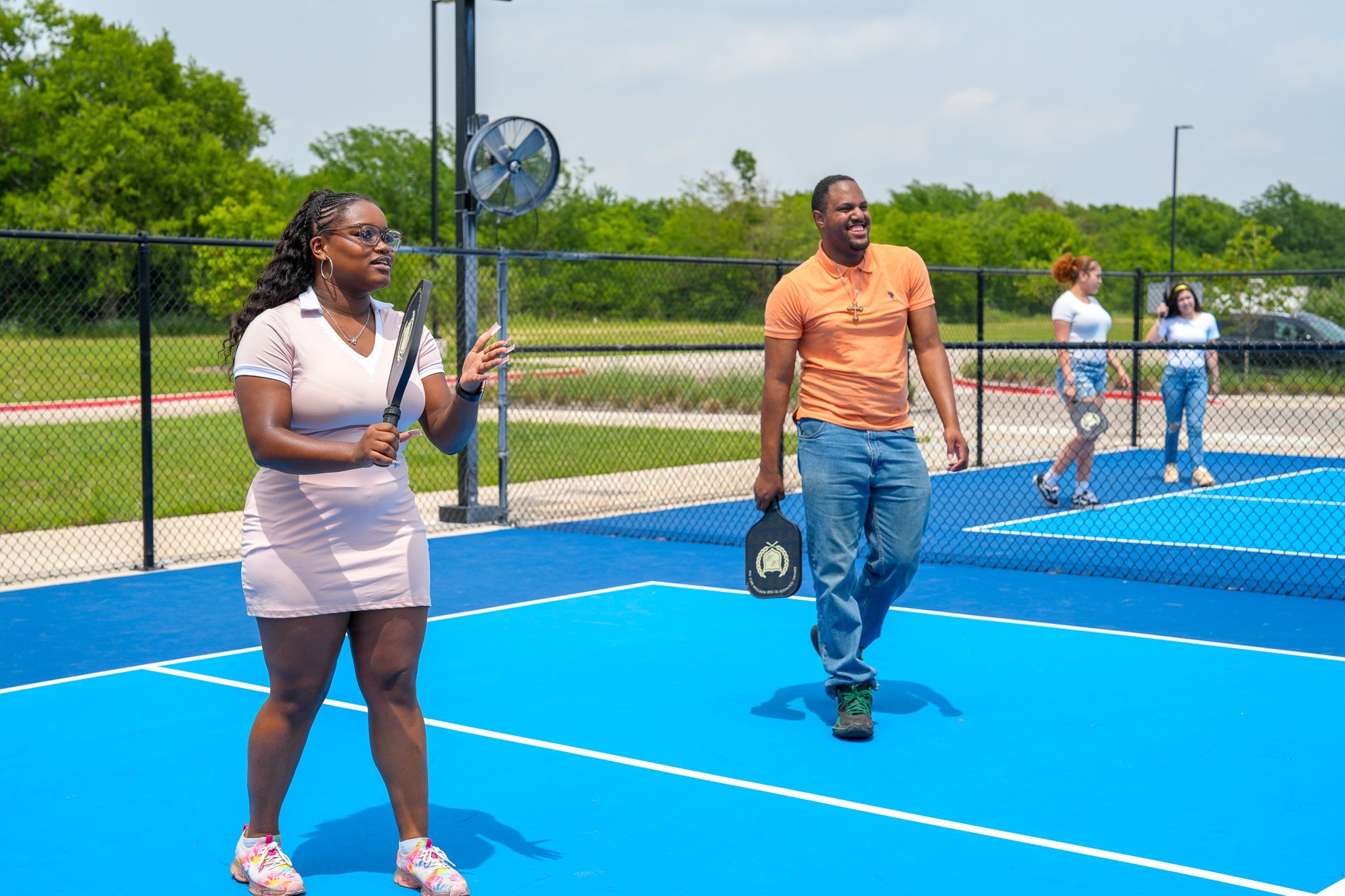 woman and man standing on pickleball court with paddles in hand. ready to start playing