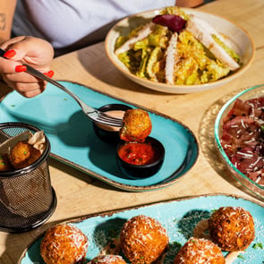 Table set with arancini, salad and more appetisers.