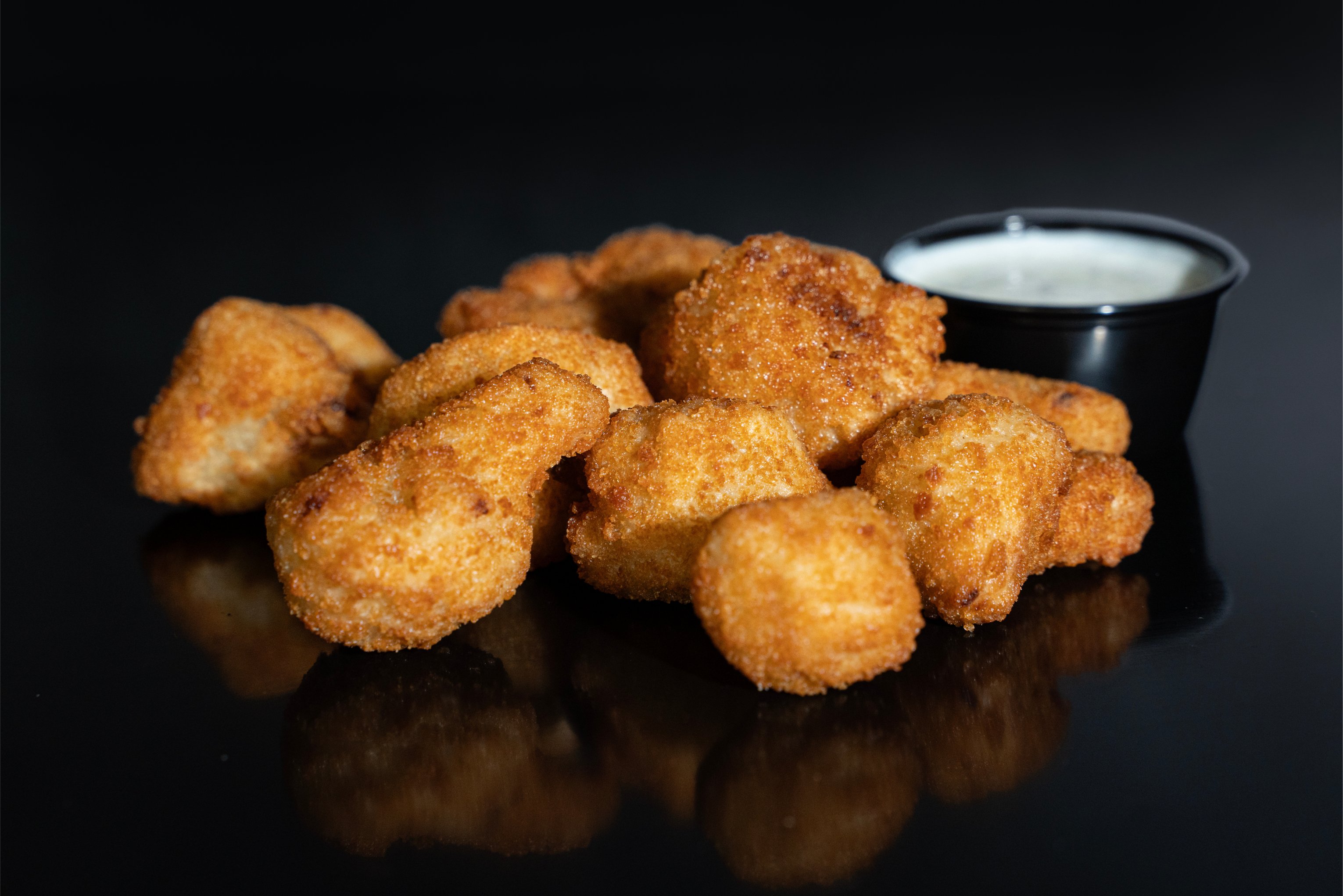 pile of cauliflower bites with ranch in the background. The item is not traditionally served with ranch
