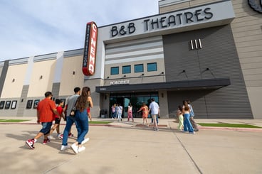 exterior of building. multiple groups of people walking towards the front door.