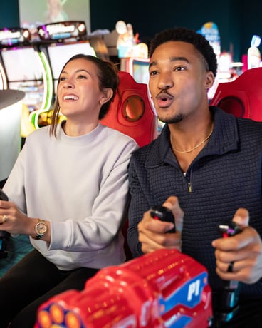 close up of a man and woman smiling and looking towards a screen.