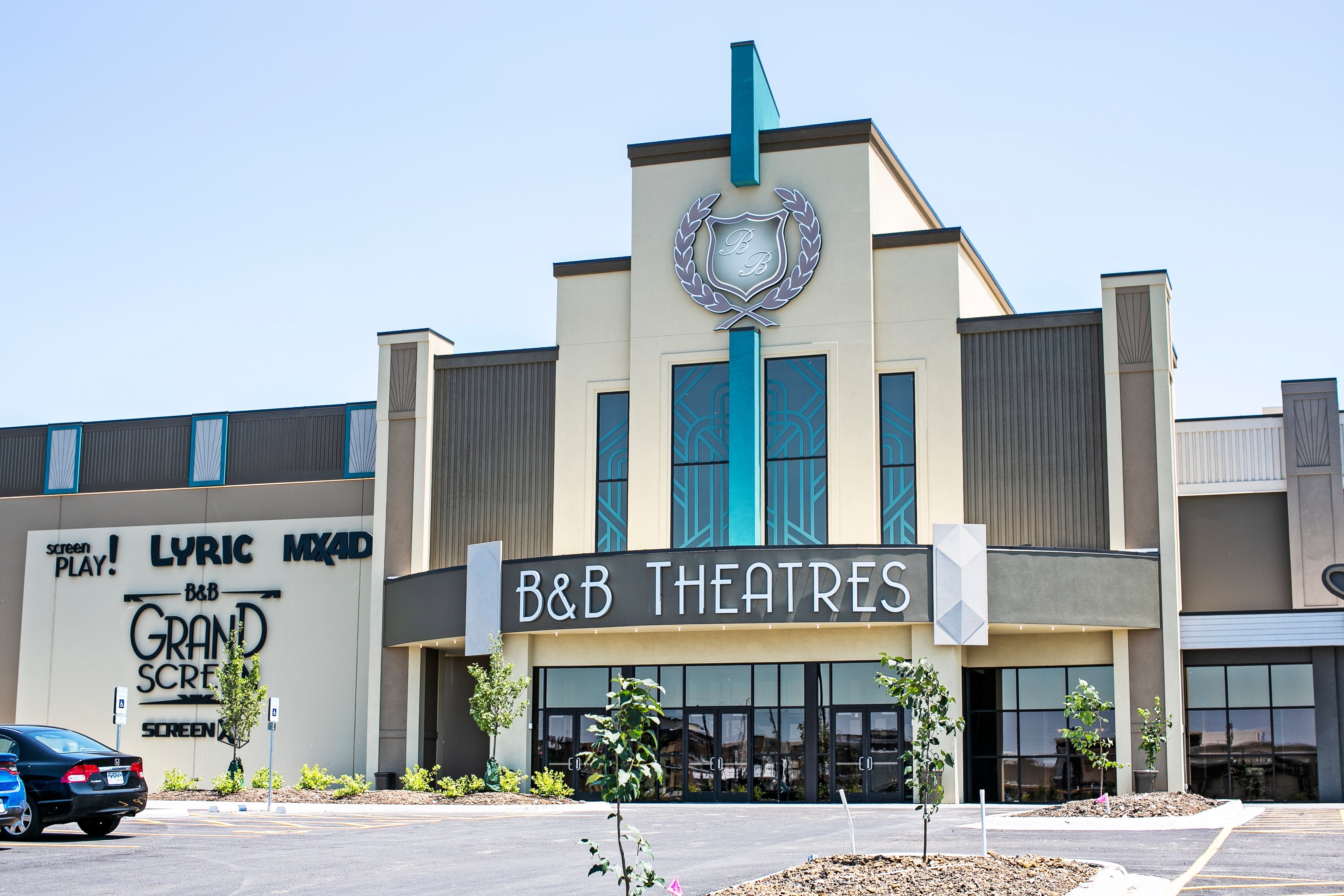 exterior of building. Shows large signage that reads B&B THEATRES, LYRIC, MX4D, B&B Grand Screen, ScreenX