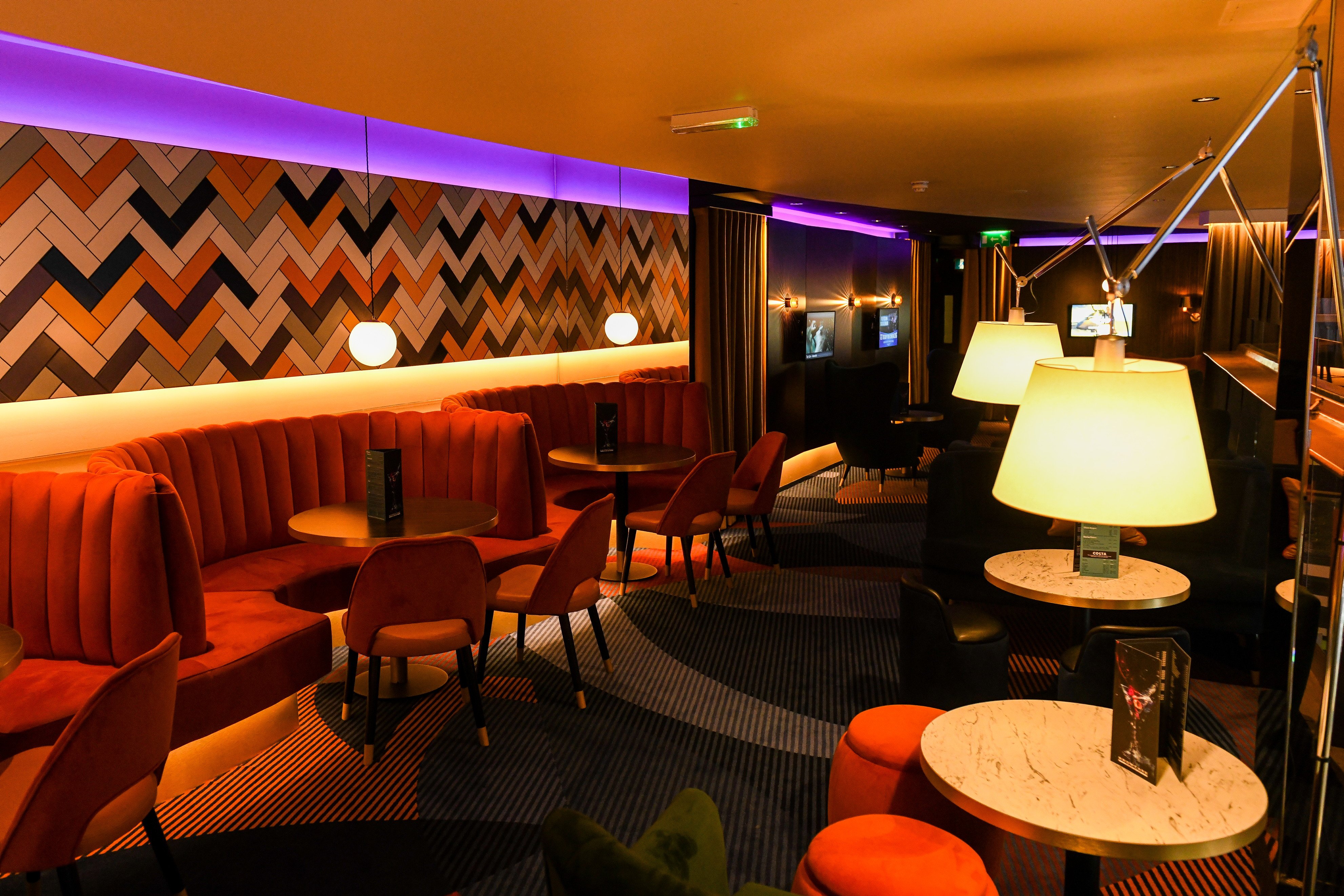 a bar with stools and blue and gold lighting