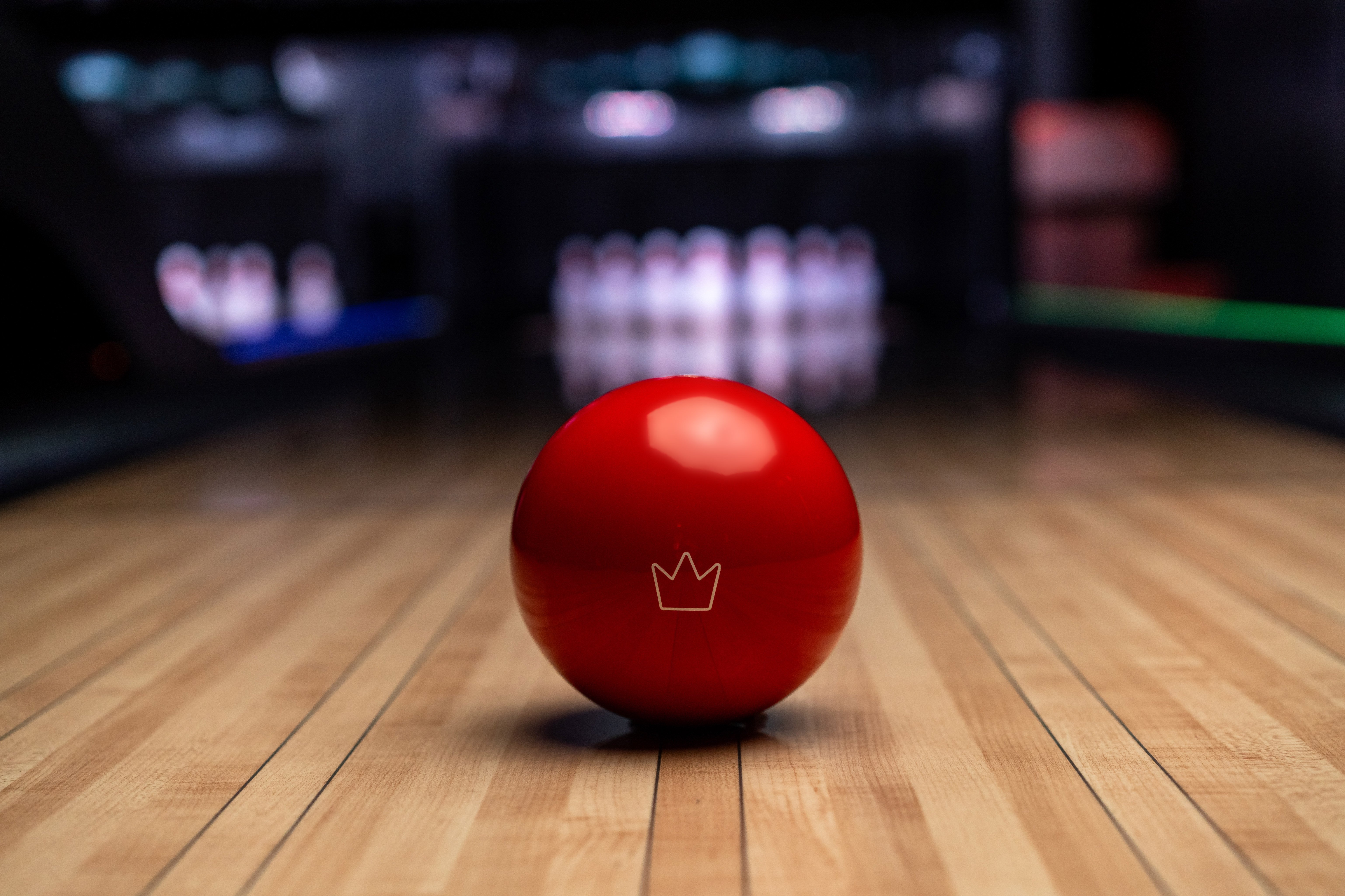 red ball sitting on lane in foreground. pins in background