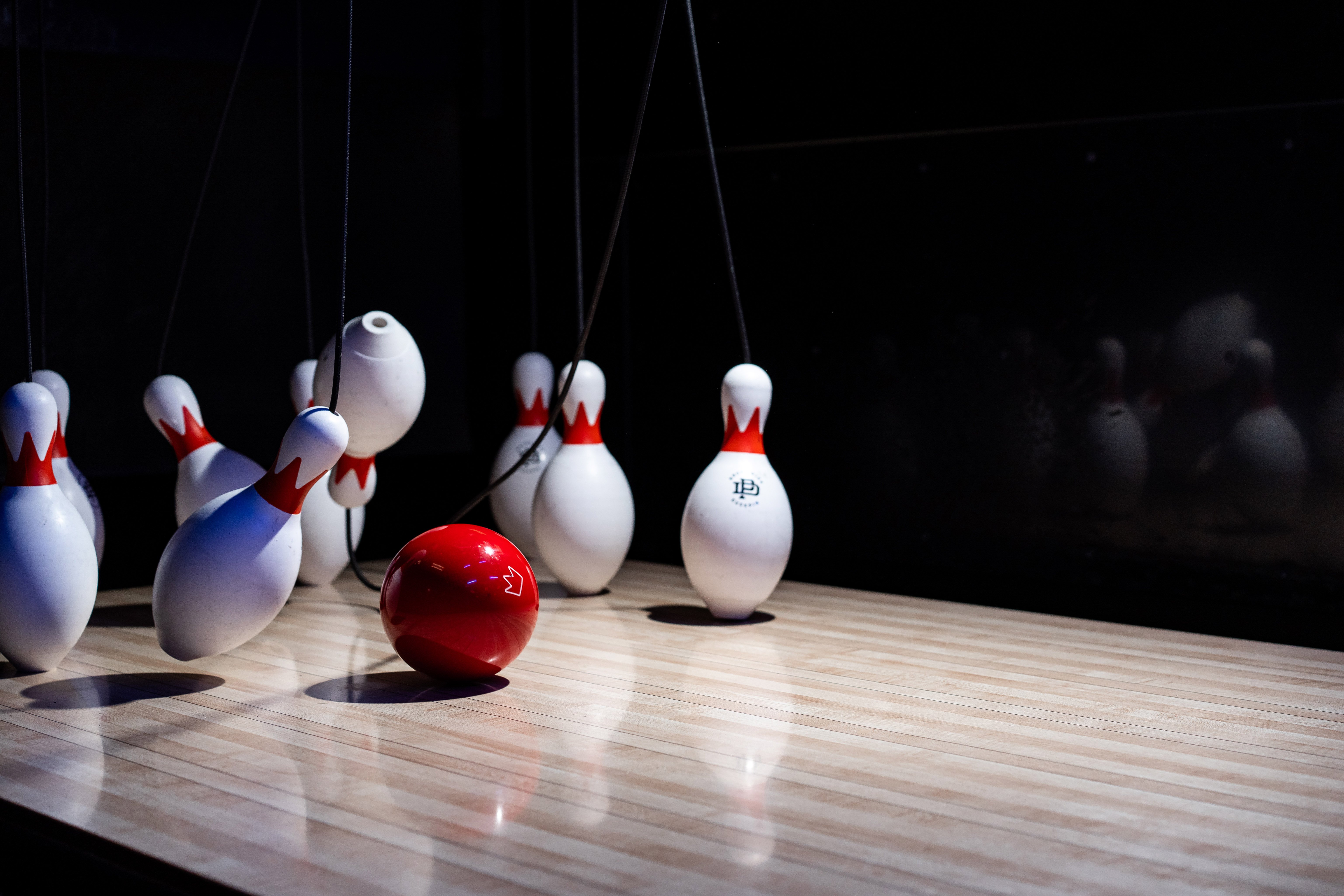 red small duckpin ball rolling into pins. some pins falling over